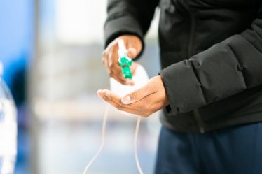 person in black jacket holding green and white plastic bottle